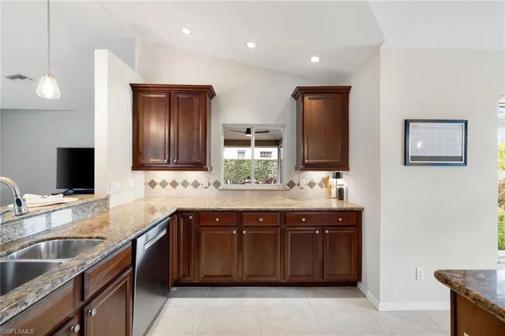 Kitchen with tasteful backsplash, lofted ceiling, visible vents, a sink, and dishwasher