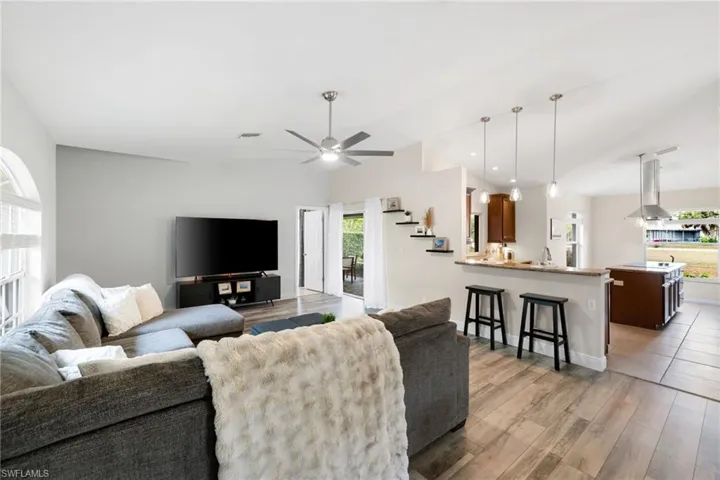 Living area featuring lofted ceiling, light wood finished floors, visible vents, and a ceiling fan