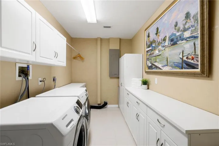 Clothes washing area with light tile patterned floors, cabinet space, visible vents, washer and dryer, and electric panel