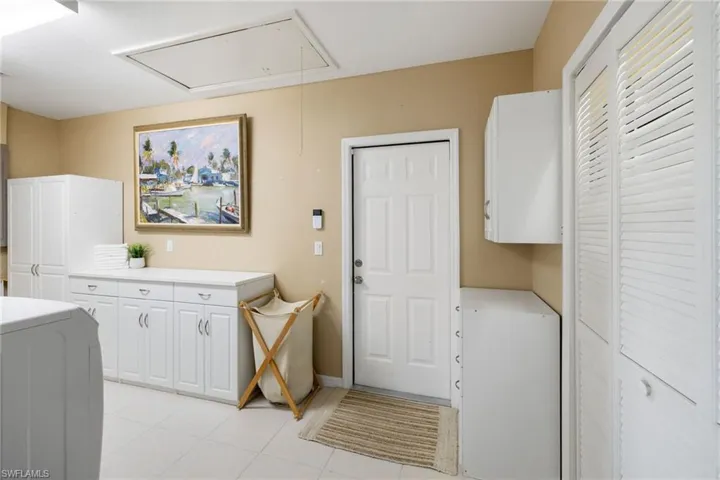 Laundry room with cabinet space, attic access, and light tile patterned floors
