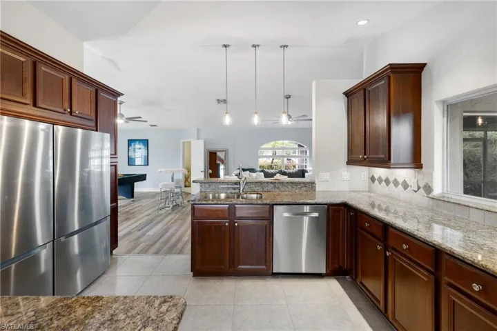 Kitchen featuring appliances with stainless steel finishes, a sink, a peninsula, and a ceiling fan