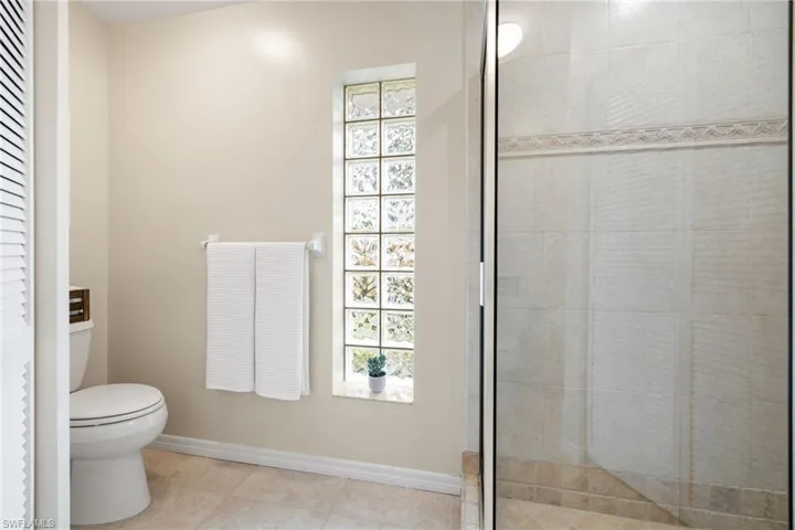 Full bathroom featuring toilet, baseboards, a tile shower, and tile patterned floors