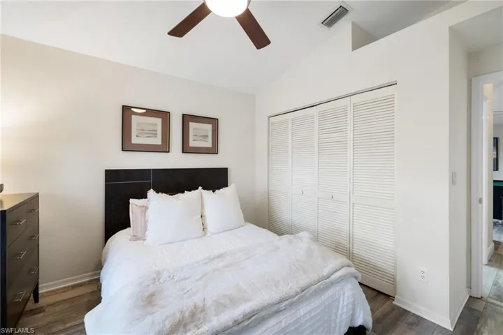 Bedroom with vaulted ceiling, dark wood-type flooring, a closet, and visible vents