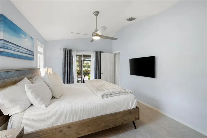 Bedroom with light tile patterned floors, visible vents, ceiling fan, vaulted ceiling, and baseboards