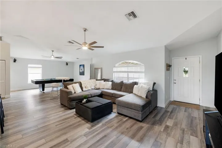 Living room featuring vaulted ceiling, visible vents, billiards, and wood finished floors