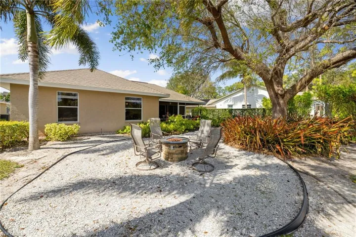 Rear view of property with roof with shingles, a fire pit, a patio, and stucco siding