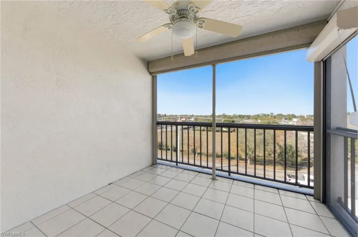 Unfurnished sunroom featuring a balcony and a ceiling fan