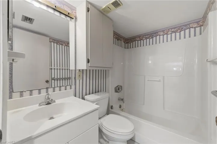 Full bath featuring wallpapered walls, bathtub / shower combination, and vanity