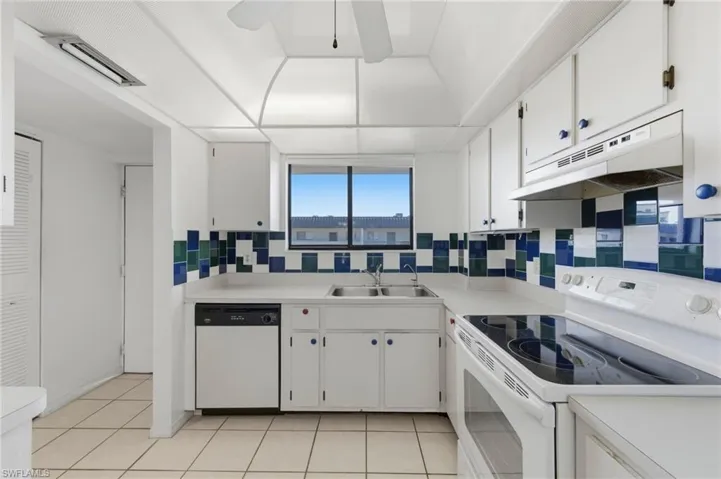 Kitchen with white appliances, white cabinetry, light countertops, and light tile patterned flooring