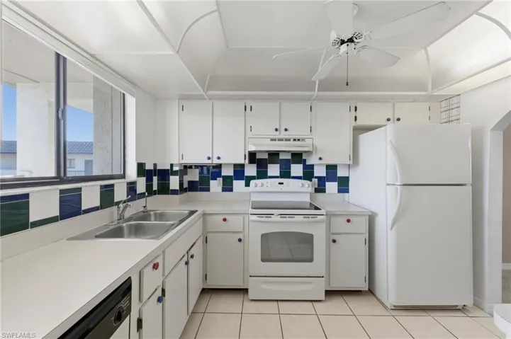 Kitchen with white appliances, white cabinetry, light countertops, ceiling fan, and tasteful backsplash