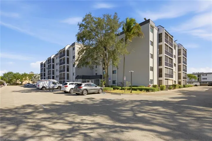 View of apartment building / complex featuring uncovered parking