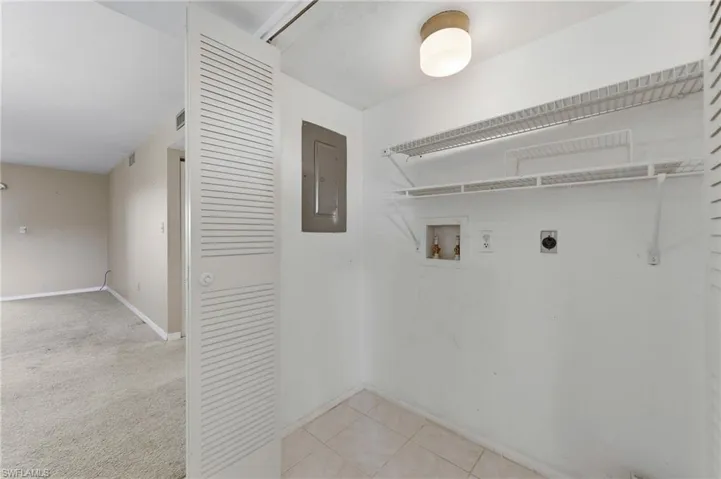 Laundry area with hookup for an electric dryer, electric panel, hookup for a washing machine, light carpet, and light tile patterned flooring