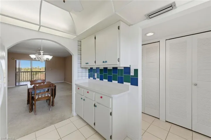 Kitchen featuring light countertops, light carpet, white cabinetry, ceiling fan, and a chandelier