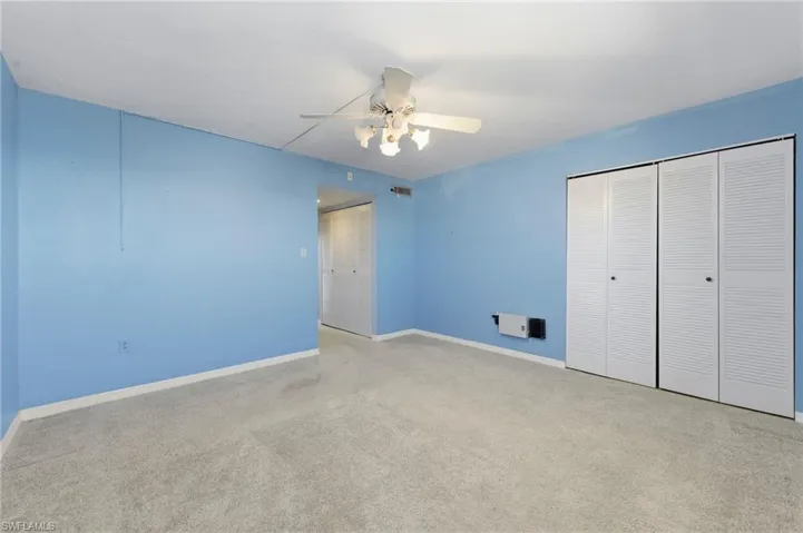Unfurnished bedroom with carpet floors, a ceiling fan, and multiple closets