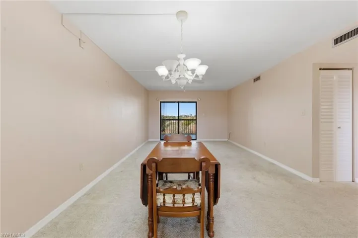 Carpeted dining space with suspended lighting and baseboards