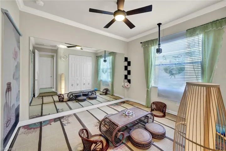 Carpeted living room featuring ceiling fan and crown molding