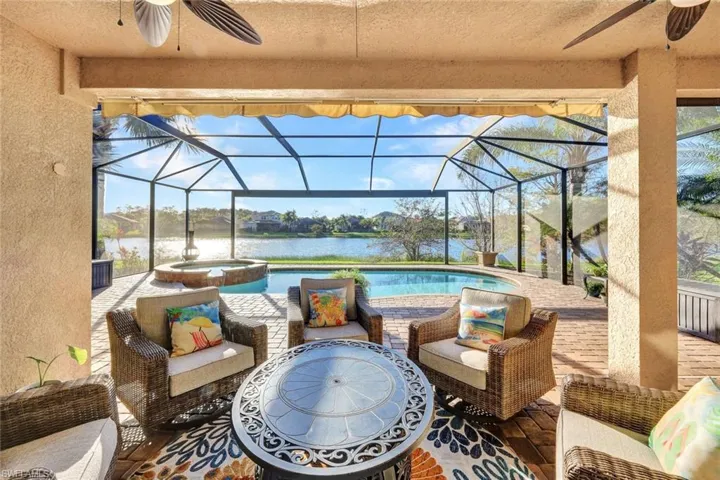 View of patio with outdoor lounge area, a water view, glass enclosure, and a pool with hot tub