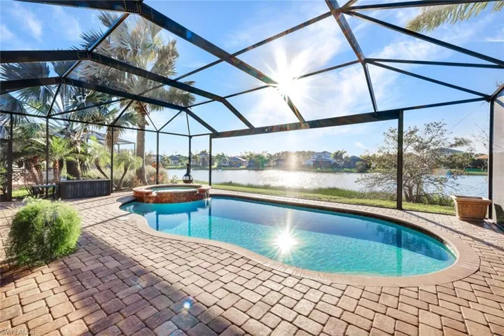 View of swimming pool featuring a lanai, a water view, an in ground hot tub, and a patio