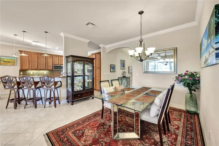 Tiled dining room featuring ornamental molding and a chandelier