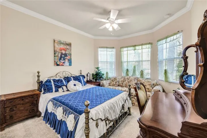 Bedroom featuring ceiling fan, light colored carpet, and ornamental molding