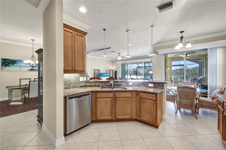 Kitchen featuring pendant lighting, dishwasher, stone counters, ceiling fan with notable chandelier, and sink
