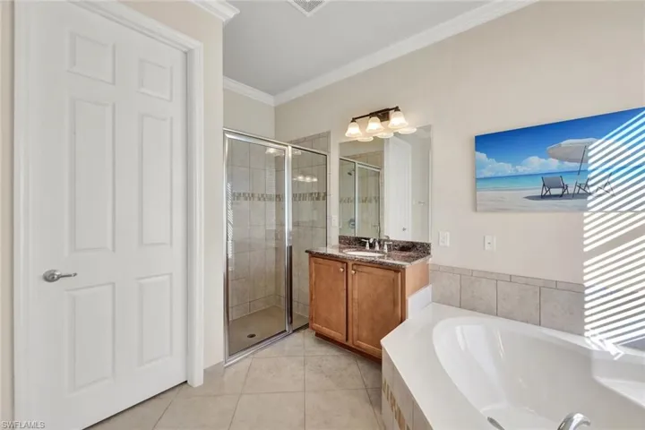 Bathroom featuring tile patterned floors, separate shower and tub, vanity, and ornamental molding