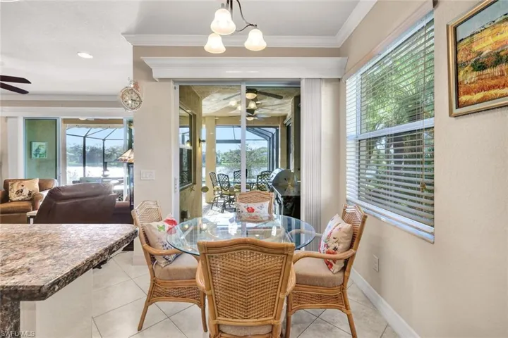 Tiled dining area featuring plenty of natural light, ornamental molding, and ceiling fan with notable chandelier