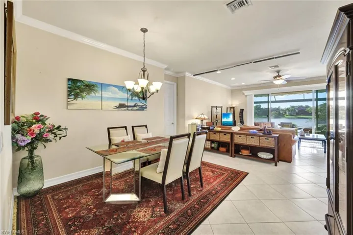Tiled dining area featuring ceiling fan with notable chandelier and ornamental molding