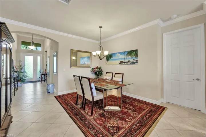Dining area featuring a chandelier, light tile patterned floors, and ornamental molding