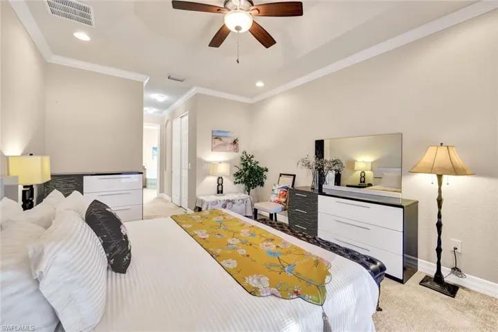 Bedroom with light carpet, ceiling fan, and ornamental molding