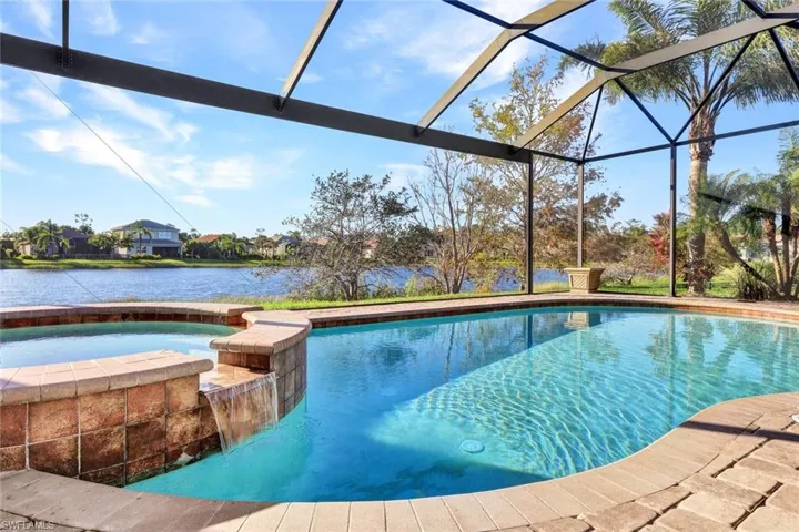 View of swimming pool with glass enclosure, a water view, and an in ground hot tub
