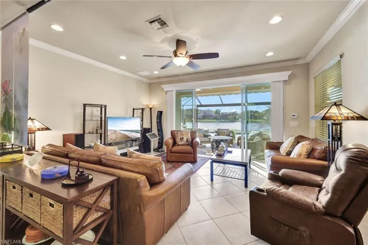 Living room with ceiling fan, crown molding, and light tile patterned flooring