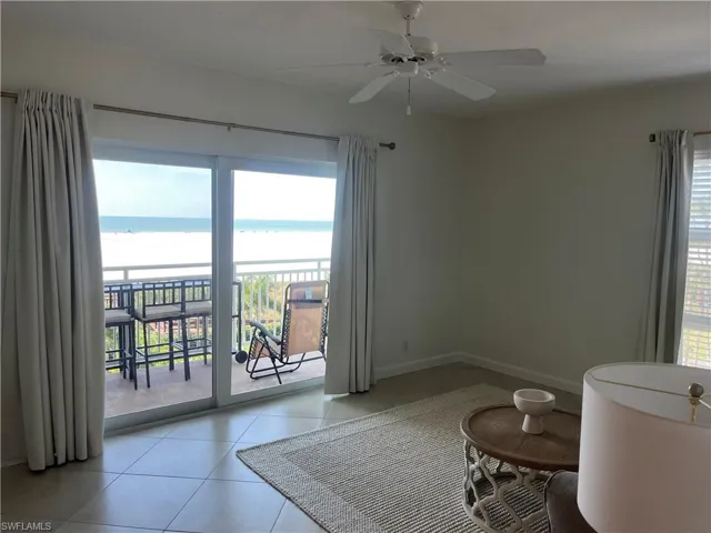 Unfurnished room with healthy amount of natural light, light tile patterned floors, a water view, and a ceiling fan