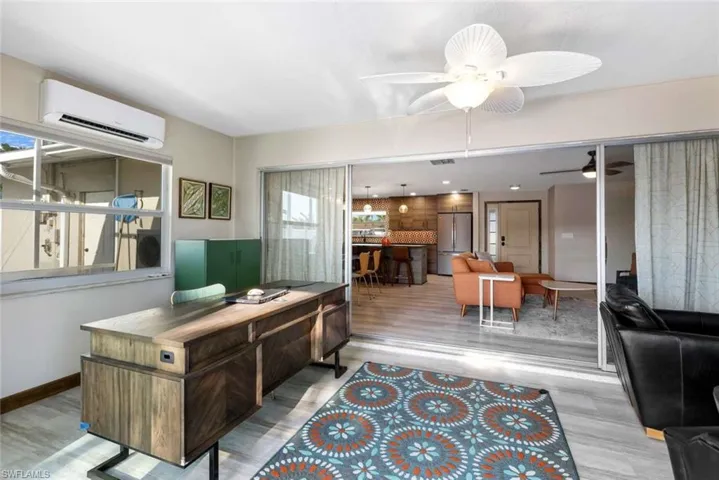 Office with a healthy amount of sunlight, a wall mounted AC, wood-type flooring, and ceiling fan