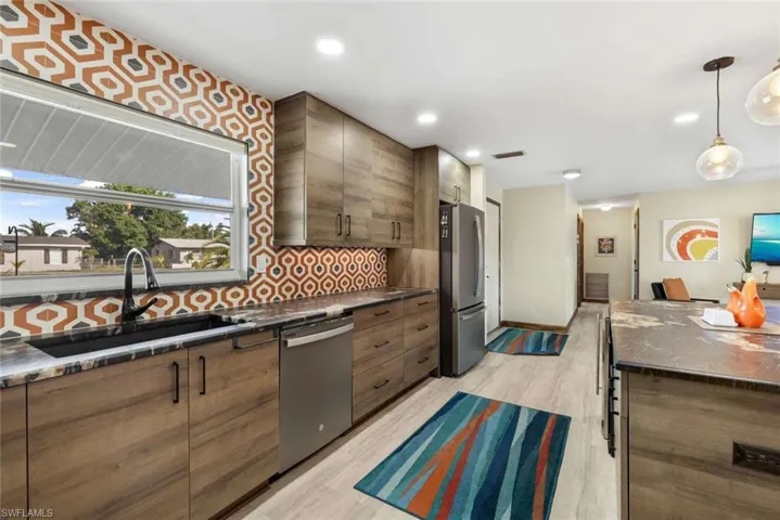 Kitchen featuring light hardwood / wood-style flooring, tasteful backsplash, stainless steel appliances, pendant lighting, and sink