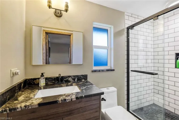 Bathroom with walk in shower, toilet, and large vanity