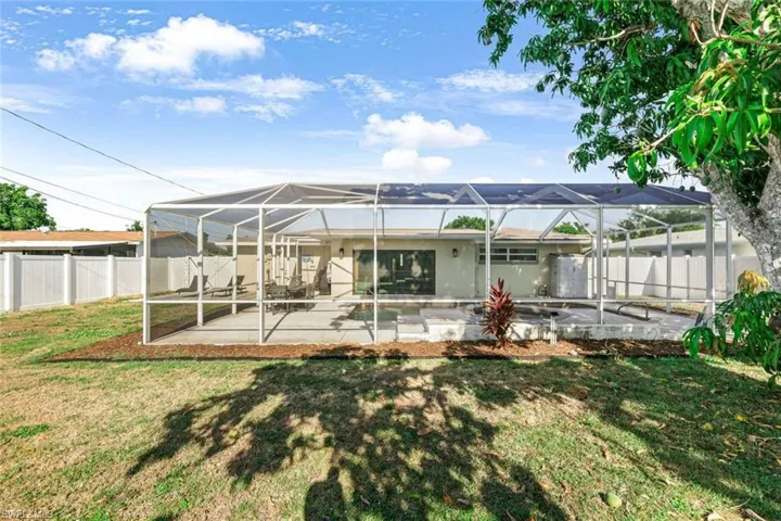 Back of property featuring a lanai, a patio area, and a lawn