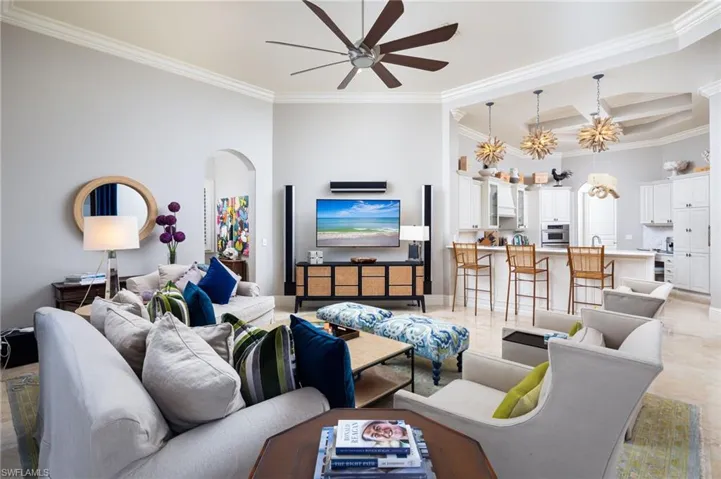 Living area featuring ornamental molding, coffered ceiling, beamed ceiling, arched walkways, and ceiling fan