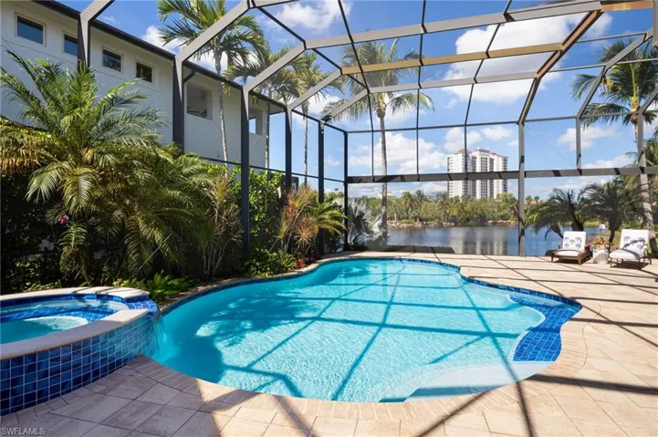 View of pool with a pool with connected hot tub, glass enclosure, a sunroom, and a patio area