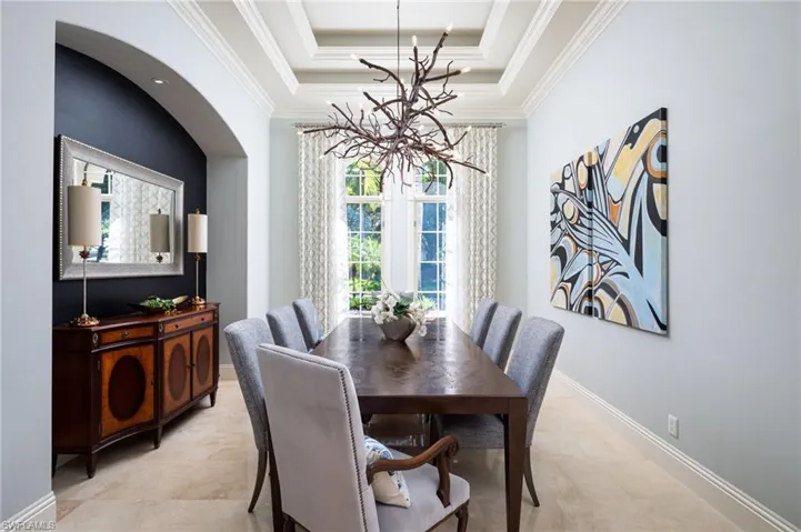 Dining room featuring a raised ceiling, a chandelier, and crown molding