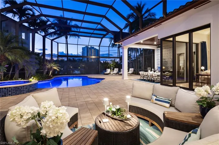 Pool at dusk featuring a patio, an outdoor living space, and glass enclosure