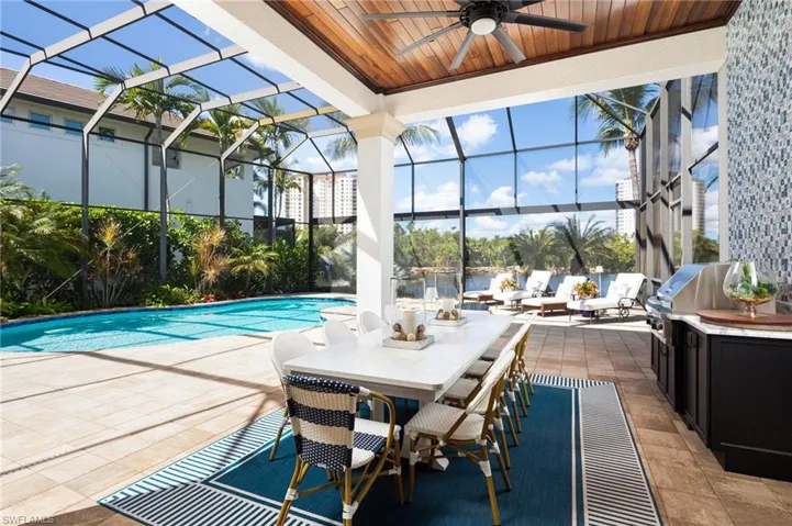 Outdoor pool with a patio, a lanai, ceiling fan, and grilling area