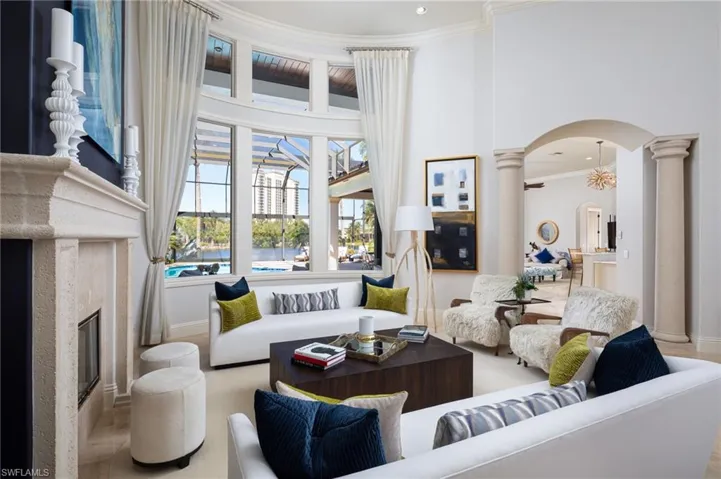 Living room with arched walkways, ornamental molding, a towering ceiling, and a premium fireplace