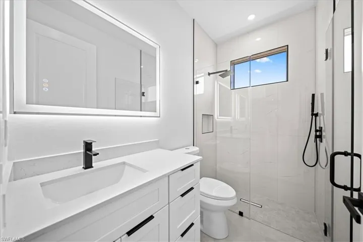 Full bathroom featuring a marble finish shower, vanity, and recessed lighting