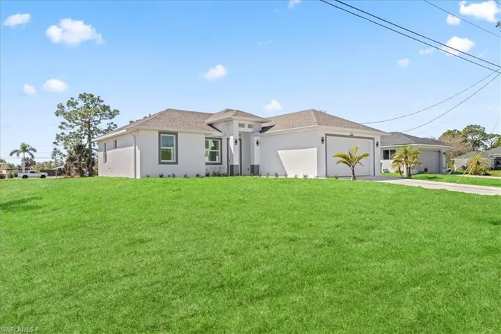 View of front of house featuring driveway, a garage, a front yard, and stucco siding