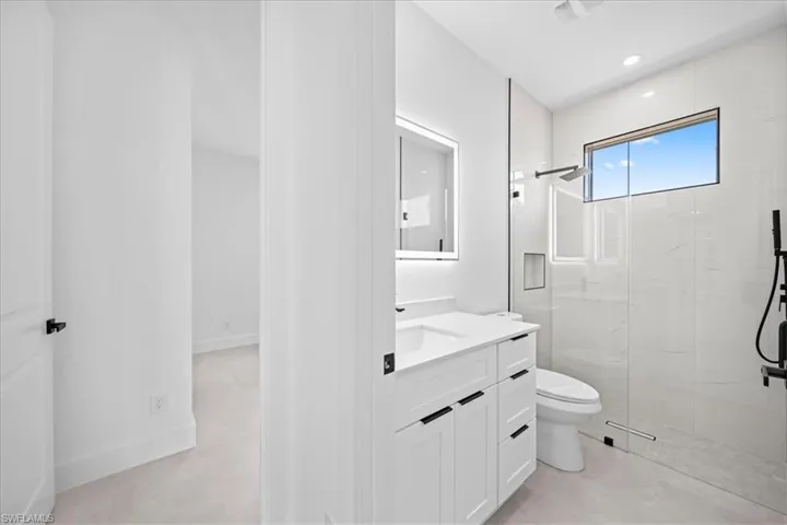 Bathroom with a marble finish shower, vanity, and recessed lighting