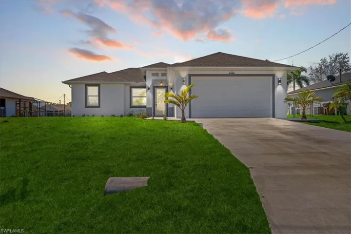 View of front facade with an attached garage, stucco siding, driveway, and a lawn