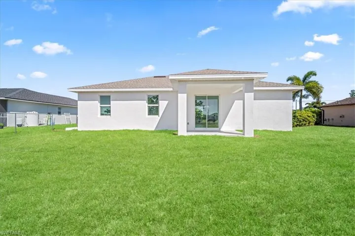 Rear view of property with a patio area, stucco siding, and roof with shingles