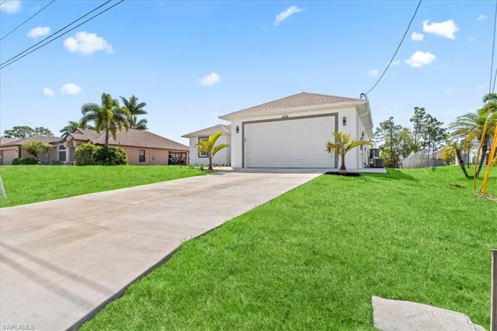 Ranch-style home with a front lawn, concrete driveway, an attached garage, and stucco siding