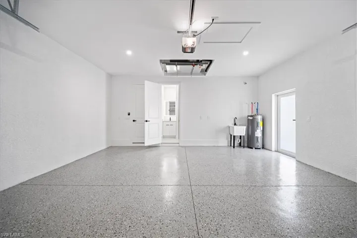 Garage featuring electric water heater, a textured wall, and recessed lighting